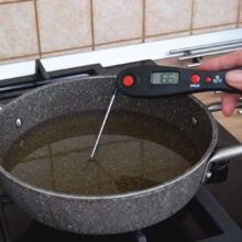 Verificarea temperaturii uleiului cu termometrul înainte de prăjirea gogoșilor lungi umplute cu ciocolată