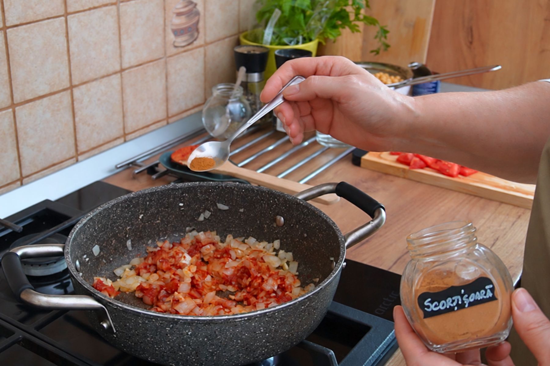 Scorțișoară adăugată peste ceapă și pasta de tomate la pregătirea sosului pentru musacaua libaneză Maghmour cu vinete și năut.