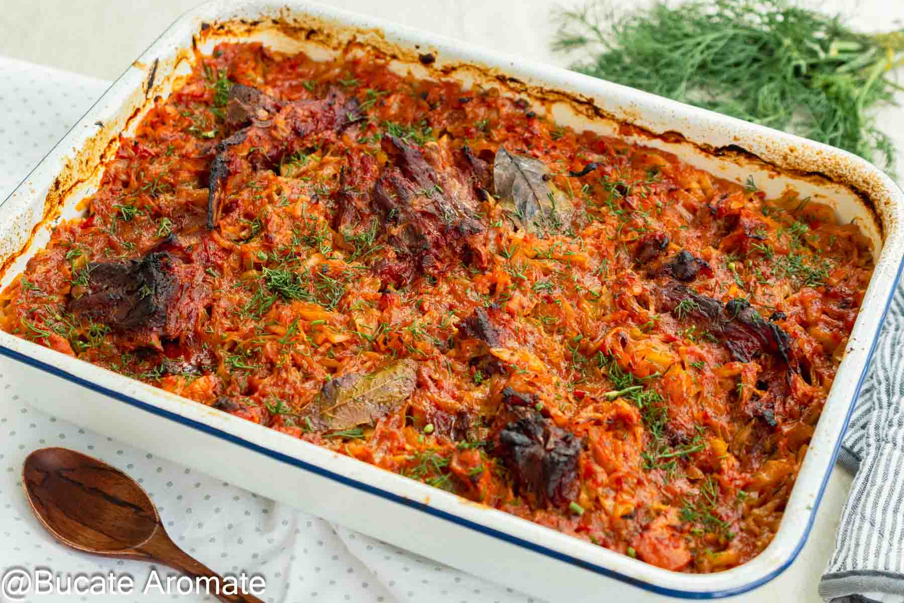 Tavă cu varză dulce, bucăți de spată de porc și oase garf afumate, gătite în sos de roșii la cuptor.