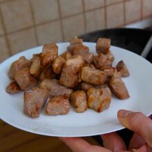 Cuburi de spată de porc rumenite în ulei și scoase pe o farfurie înainte de prepararea verzei.