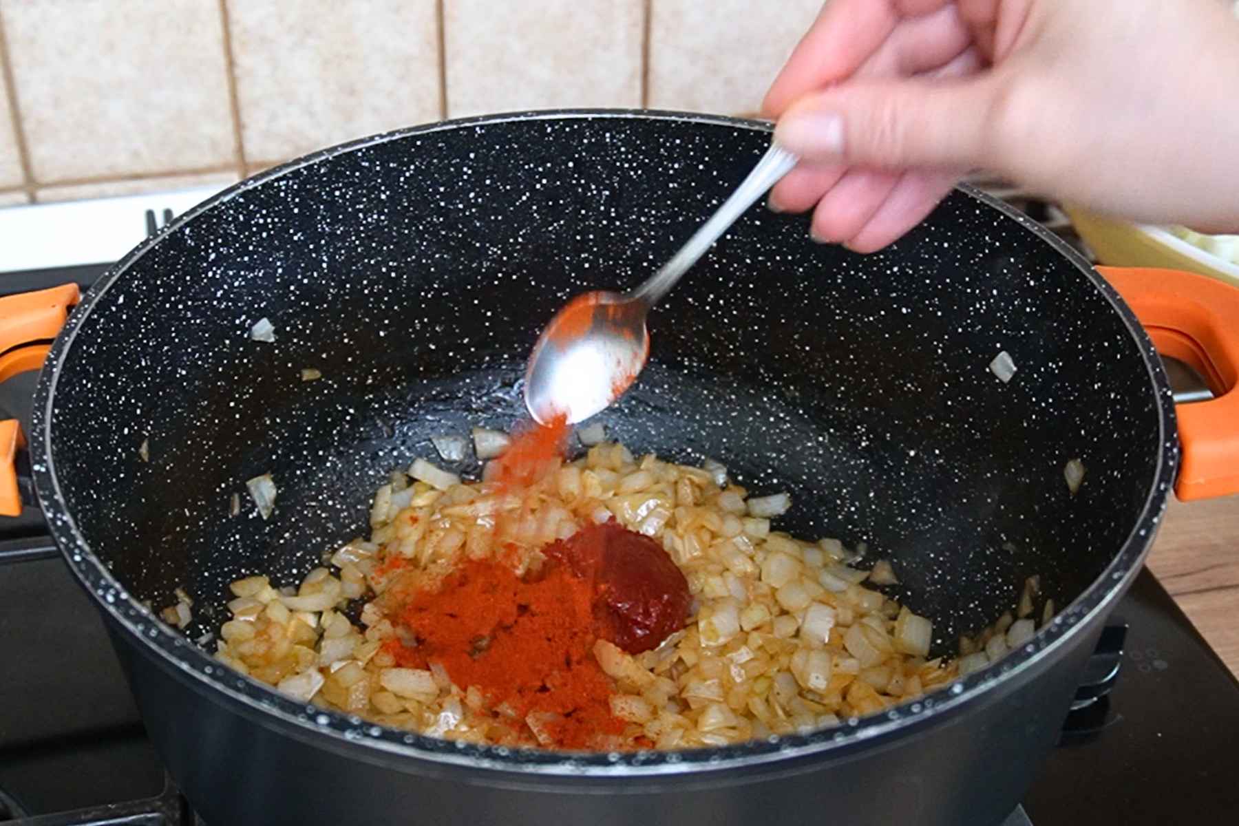 Pastă de tomate și boia dulce adăugate peste ceapa călită pentru mâncarea de varză cu carne.