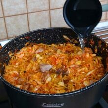 Apă turnată treptat peste varza dulce cu carne de porc pentru reglarea consistenței în timpul fierberii.