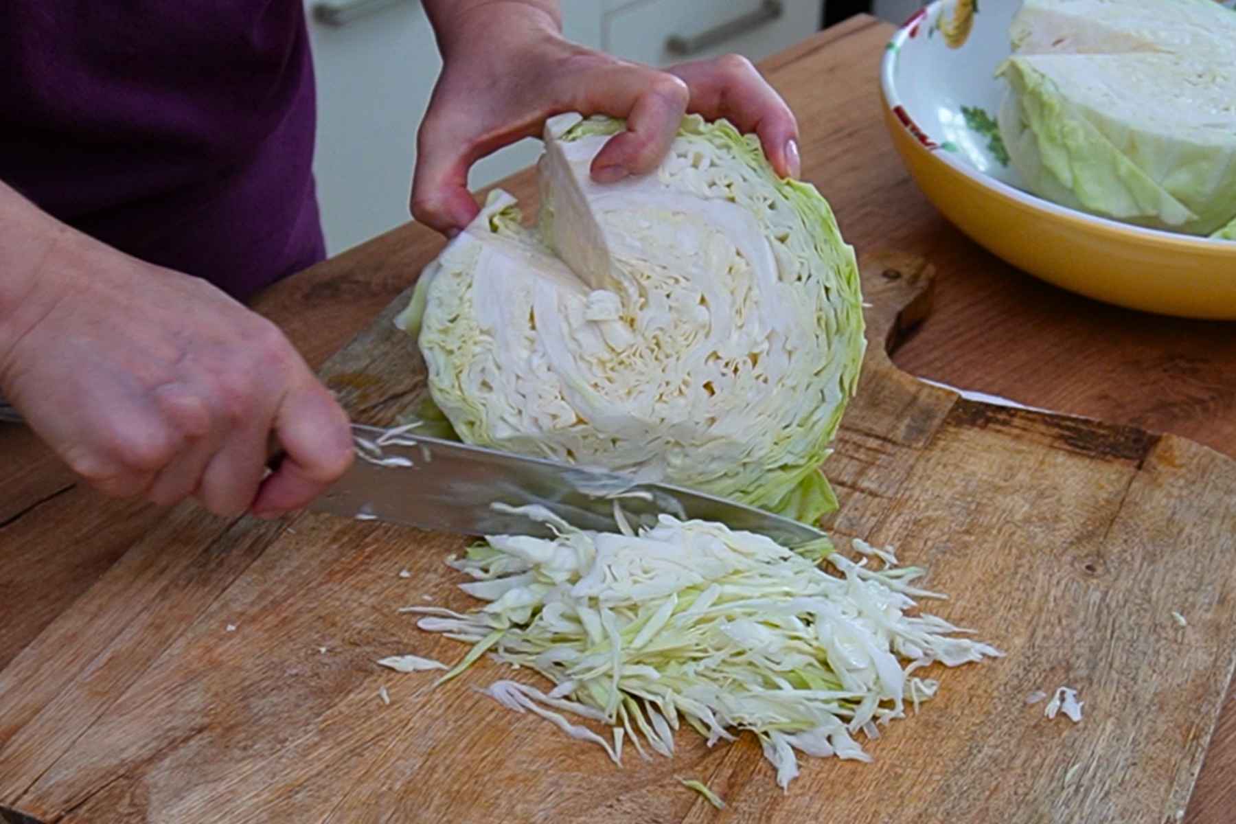 Varză albă proaspătă tăiată fideluță pe un tocător de lemn pentru mâncarea cu porc și afumătură.