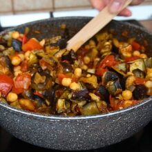 Cuburi de vinete coapte și năut adăugate în sosul aromat de roșii pentru tocănița libaneză Maghmour.