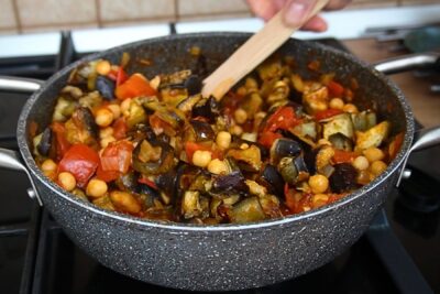 Cuburi de vinete coapte și năut adăugate în sosul aromat de roșii pentru tocănița libaneză Maghmour.