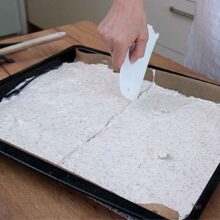 Compoziție de bezea cu nucă întinsă uniform în tavă înainte de coacere