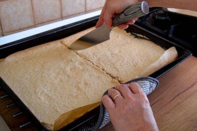 Foaie coaptă de bezea cu nucă tăiată în două pentru montarea prăjiturii Krantz