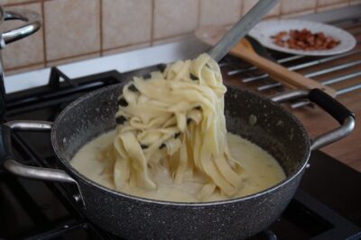 Tăiței lați de casă amestecați cu sos cremos de brânză de burduf și șunculiță