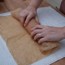 Modelarea unui baton de șuncă de pui prin rularea strânsă a amestecului de carne în hârtie de copt, fără membrană pentru salam.